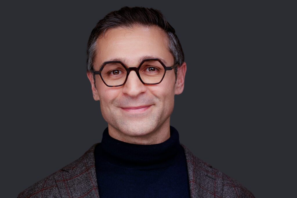 Volume headshot from TREF, smiling man in glasses